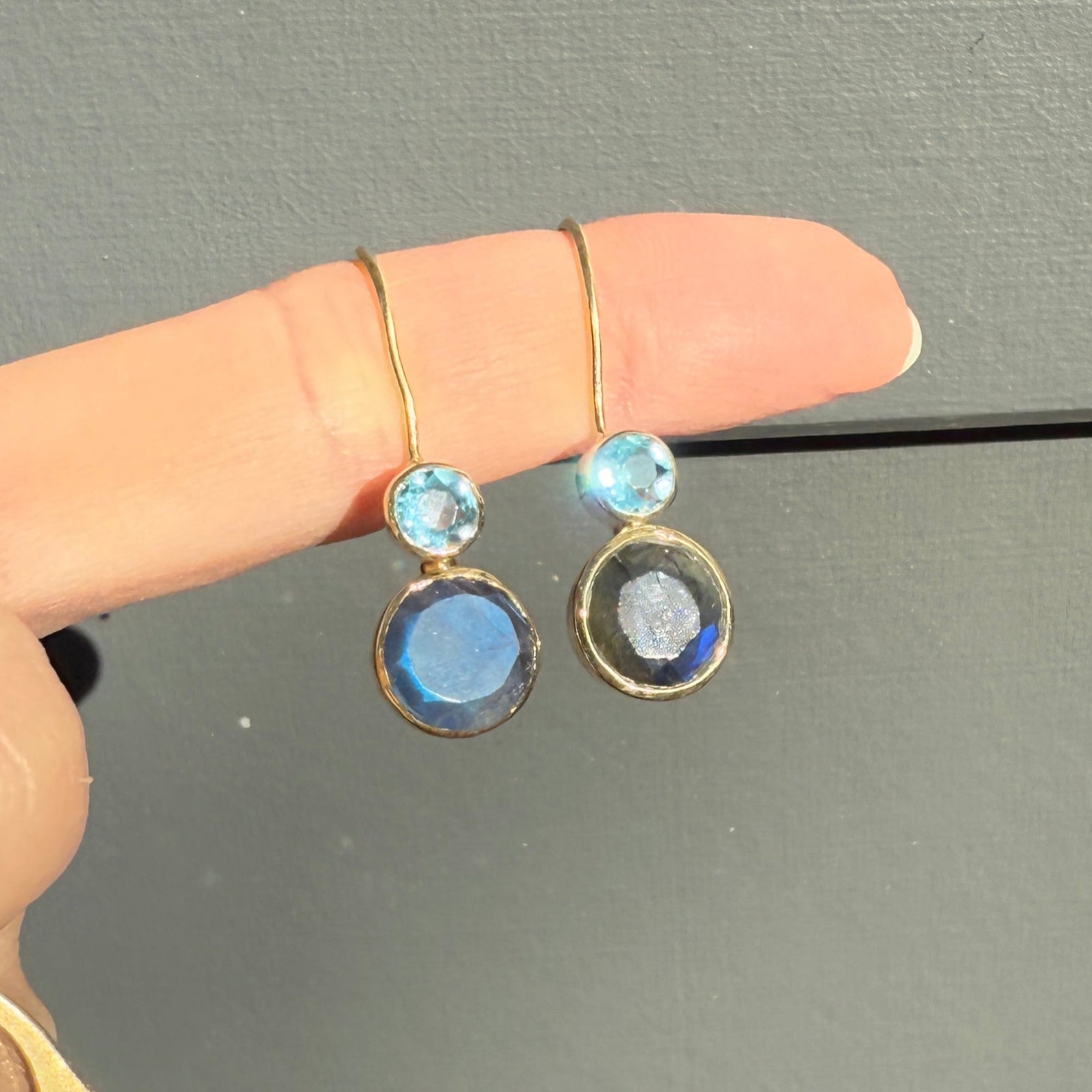 Hand wearing two rings with gemstones on a gray background